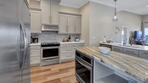 Una cocina moderna con electrodomésticos de acero inoxidable, armarios blancos y una encimera de mármol.