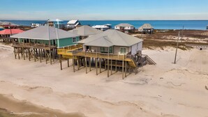 A beachfront property with multiple wooden decked houses, some with attached porches, overlooking the ocean. - Salty Piece of Land | Nightly openings 8/22. Pool. (Dauphin Island)
