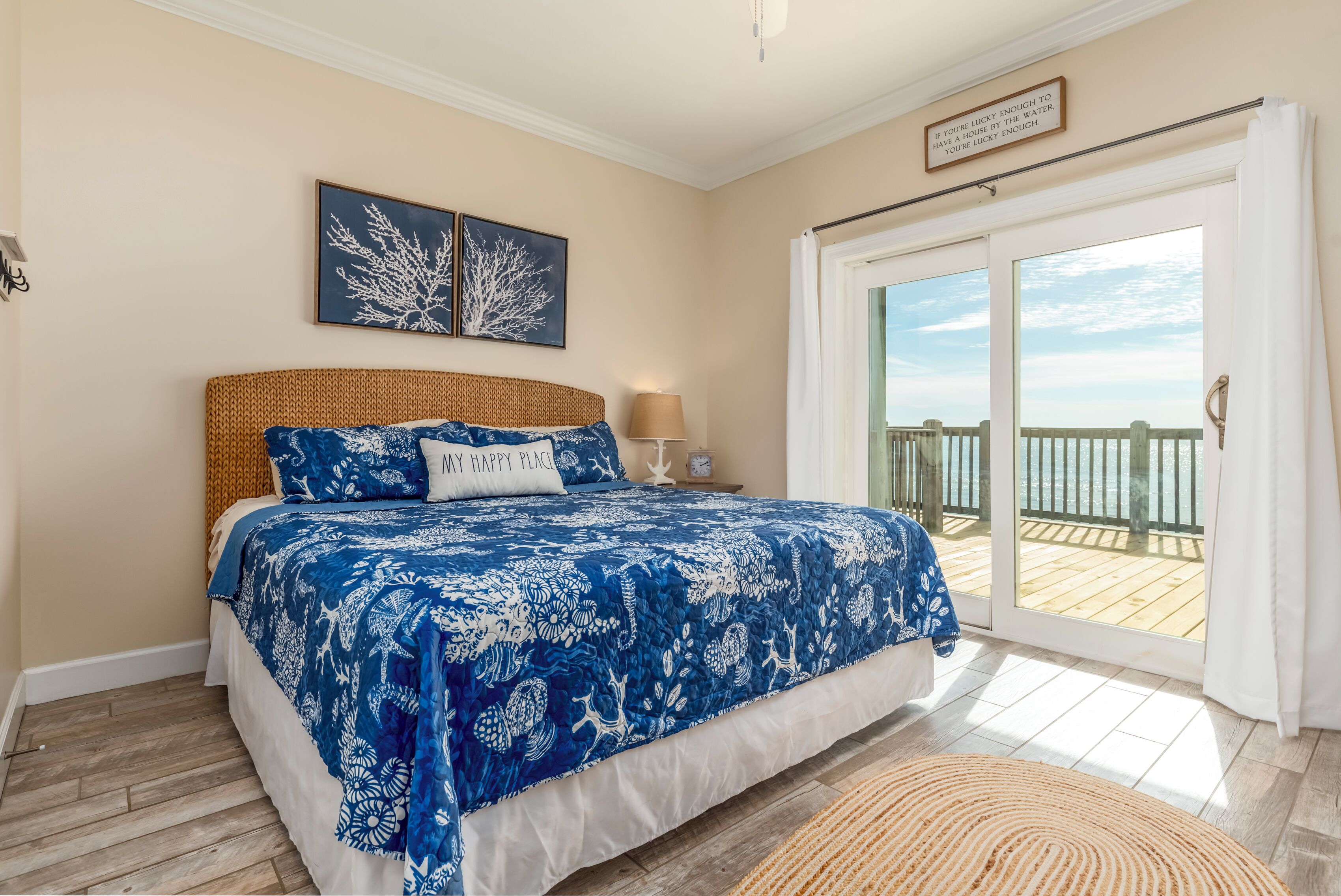 A bedroom with a large bed, a nightstand, a lamp, and a view of the balcony.
