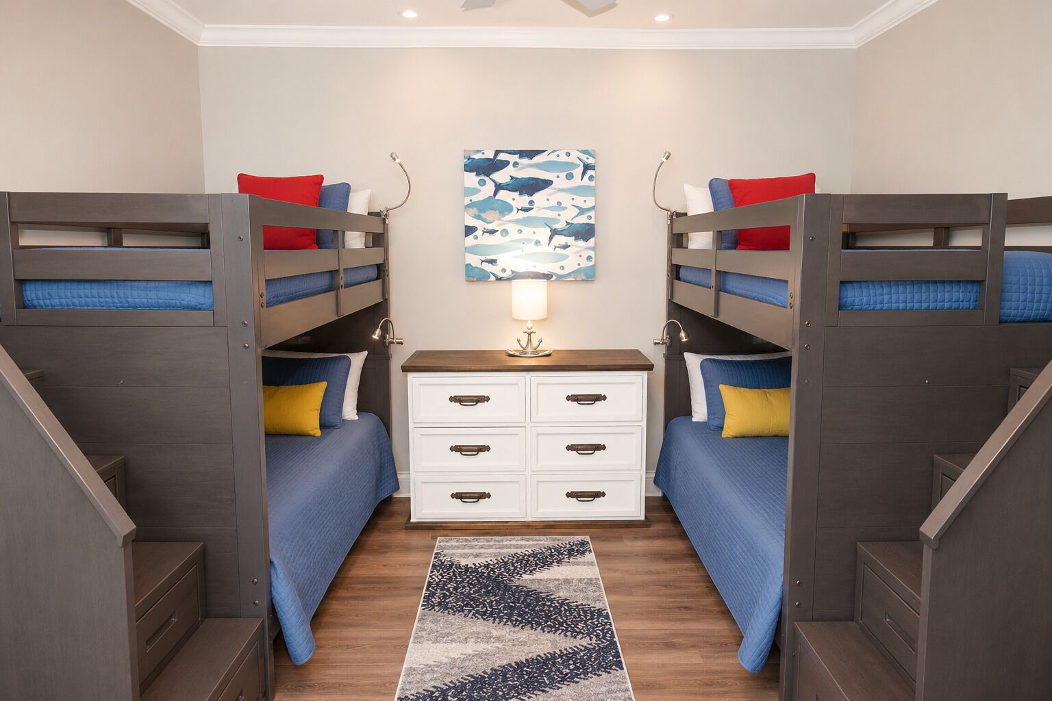 A bunk bed room with a central nightstand, a patterned rug, and a wall art piece.