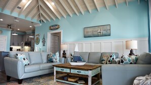 A living room with two light blue sofas, a wooden coffee table, and nautical-themed decor.