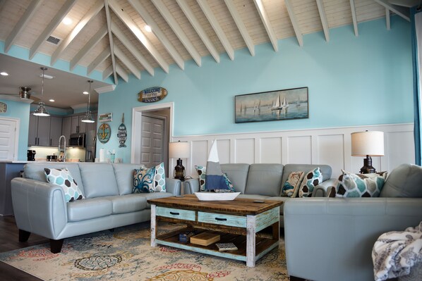 A living room with two light blue sofas, a wooden coffee table, and nautical-themed decor.
