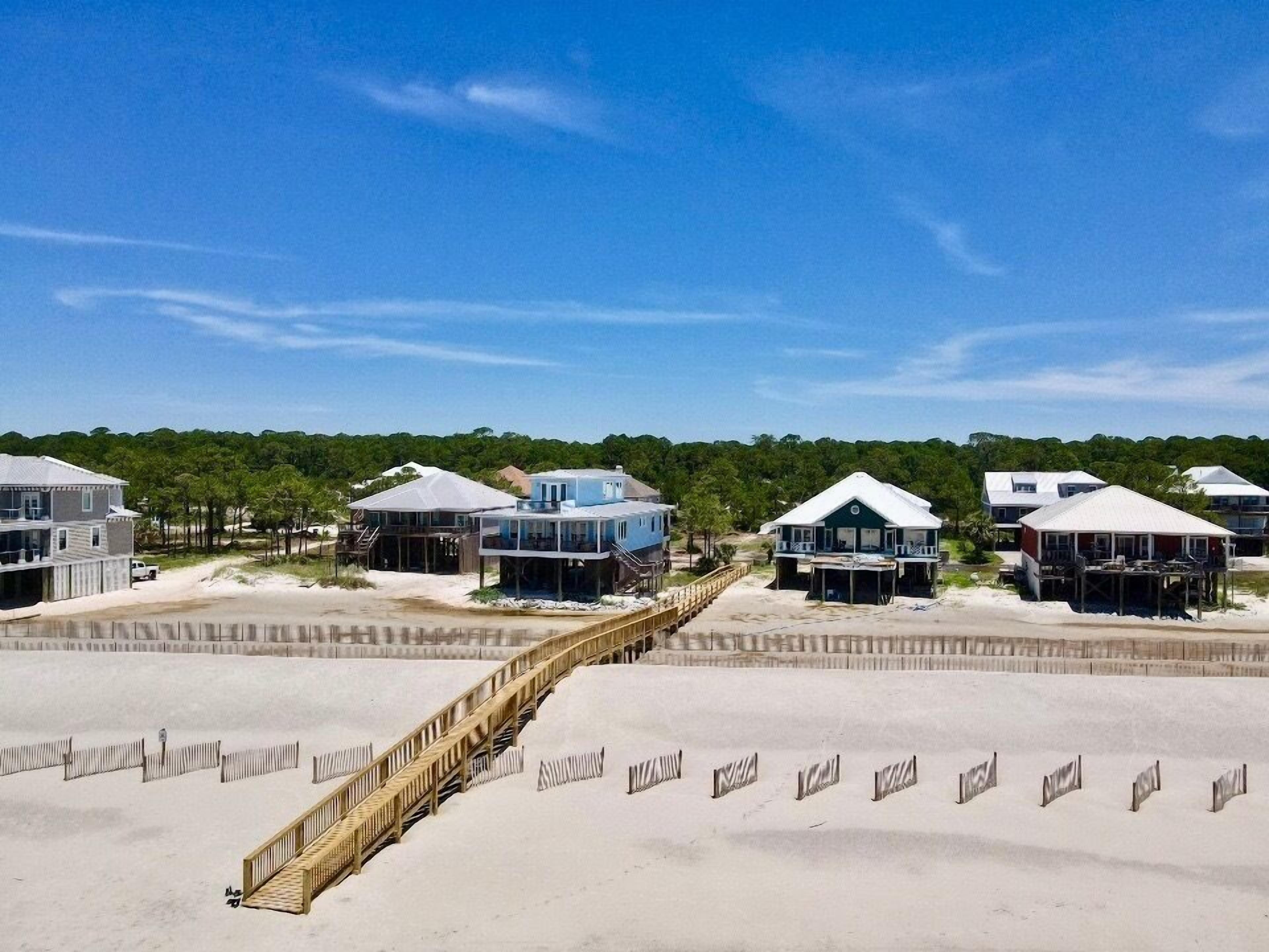 A beachfront property with multiple houses connected by a wooden boardwalk.