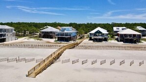 A beachfront property with multiple houses connected by a wooden boardwalk.