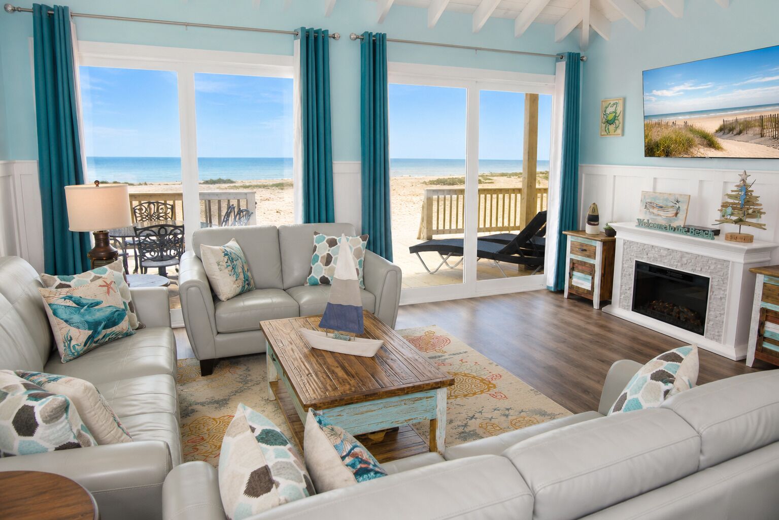Ein Wohnzimmer direkt am Strand mit einer Couch, einem Couchtisch und einem Kamin.