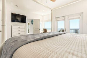 Un dormitorio con una cama grande, televisión, cómoda y vistas al océano.