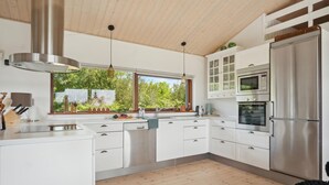 Una cucina moderna con mobili bianchi, elettrodomestici in acciaio inossidabile e soffitto in legno.