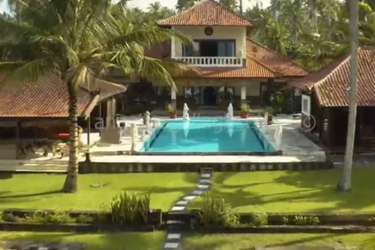 A pool area with a clear blue pool, surrounded by a well-maintained lawn and palm trees.