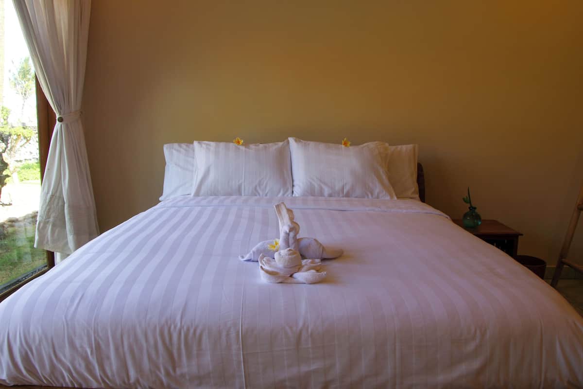 A neatly made bed with white linens and a towel sculpture on the bed.
