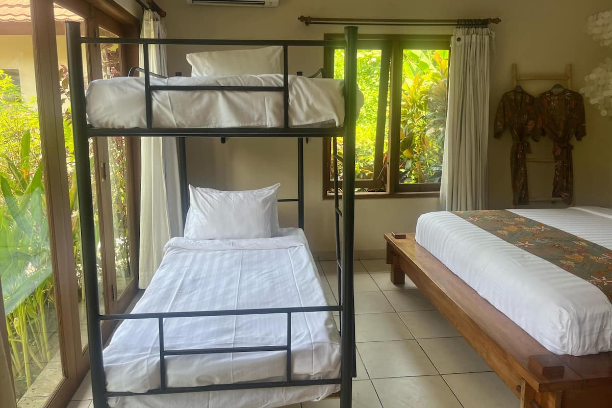 A bunk bed room with a window, a wooden bench, and a bed with a patterned bedspread.