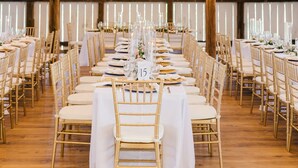A long banquet table with white tablecloths and gold chairs, set up in a rustic hall with wooden beams and a chandelier. - 7 Bedrooms, 2 Houses all for 1 Price, 5 BR Large House & 2 BR Carriage House (Morgantown)