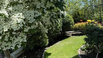 A garden with a well-maintained lawn, a stone pathway, and various shrubs and trees.