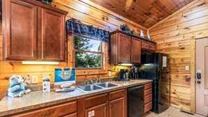 A wooden cabin kitchen with a sink, stove, and refrigerator. - Lovin' the View - Gorgeous views plus a true cabin feel! (Gatlinburg)