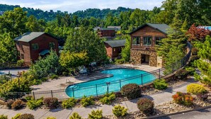 A pool area with a circular pool, surrounded by a stone wall and a metal fence. - Lovin' the View - Gorgeous views plus a true cabin feel! (Gatlinburg)