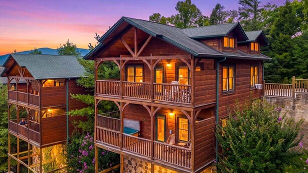 A multi-story wooden cabin with balconies, surrounded by lush greenery. - Lovin' the View - Gorgeous views plus a true cabin feel! (Gatlinburg)
