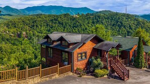 A cabin with a wooden exterior, a porch, and a view of a forested mountain range. - Lovin' the View - Gorgeous views plus a true cabin feel! (Gatlinburg)