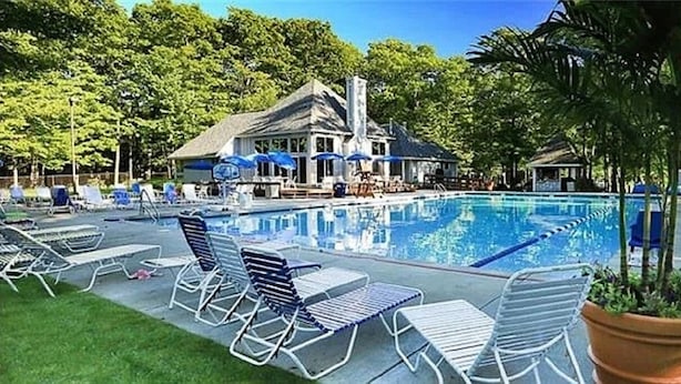 A swimming pool with lounge chairs and umbrellas, surrounded by trees and a building with a sloped roof. - Peaceful Retreat in Hidden Valley, PA: Ski Resort, Golf and Trails in Mountain (Somerset)