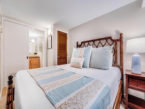 Een slaapkamer met een groot bed, houten hoofdbord en een nachtkastje met een lamp.