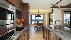 Una cucina moderna con mobili in legno, elettrodomestici in acciaio inossidabile e vista sull'oceano.