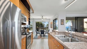 Una cocina moderna con electrodomésticos de acero inoxidable, armarios de madera y encimeras de granito, con vistas al exterior.