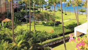 A resort with a well-maintained lawn, palm trees, and a view of the ocean. - Iconic Ocean & Mountain Views | Corner Residence w/ Resort Amenities (Lahaina)