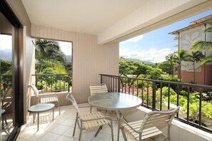 Enjoy a serene view of the lush landscape from this balcony with a round table and four comfortable chairs.