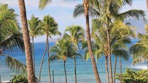A tropical resort with palm trees, a clear view of the ocean, and a well-maintained lawn. - Iconic Ocean & Mountain Views | Corner Residence w/ Resort Amenities (Lahaina)