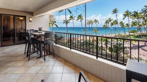 Ein Balkon mit Blick auf den Strand und das Meer, ausgestattet mit einem Essbereich inklusive Stühle und Tisch.