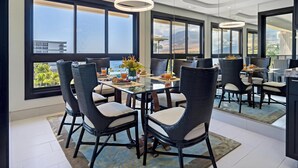 Un espace repas moderne avec une table en verre, des chaises en osier et une vue sur les montagnes.