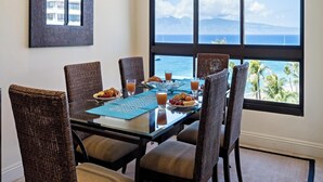 A dining area with a table set for four, overlooking a scenic ocean view.