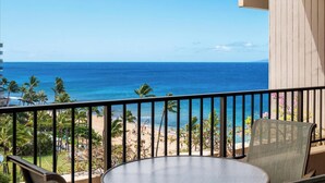 A balcony with a view of the ocean and beach, featuring a round table and chairs. - Panoramic Ocean Views | 3BR Sleeps 6 w/ Private Lanai (Lahaina)