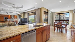 A modern kitchen with a large island, built-in appliances, and a dining area with a view. - Panoramic Ocean Views | 3BR Sleeps 6 w/ Private Lanai (Lahaina)