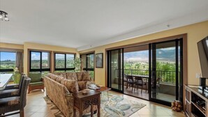 A spacious living area with a sofa, chairs, a coffee table, and a balcony with a view. - Mountain, Golf, and Sunrise Views - Kaanapali Alii 475 (Lahaina)