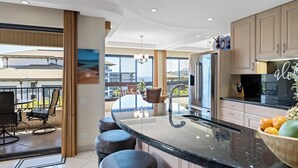 Una cocina moderna con una isla grande, electrodomésticos de acero inoxidable y vista al océano.