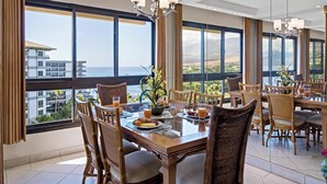 Un comedor con vista al océano, ventanas amplias y sillas de mimbre.