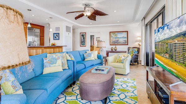 Relax in this inviting living room with a plush sofa, round ottoman, and beach-inspired artwork.