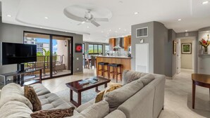Een moderne woonkamer met een bank, salontafel, televisie en een balkon met uitzicht.