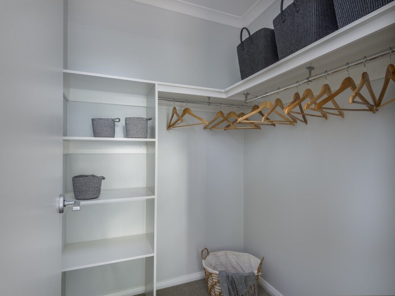 A walk-in closet with open shelves, a hanging rod, and a chair.