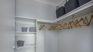 Un vestidor con estantes abiertos, una barra para colgar ropa y una silla.