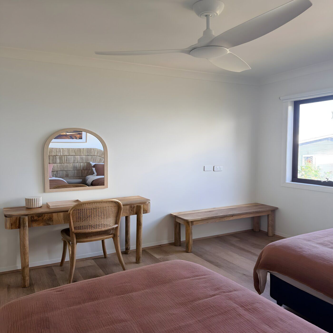 Un dormitorio con cama, escritorio con silla, lámpara de pie y ventilador de techo.
