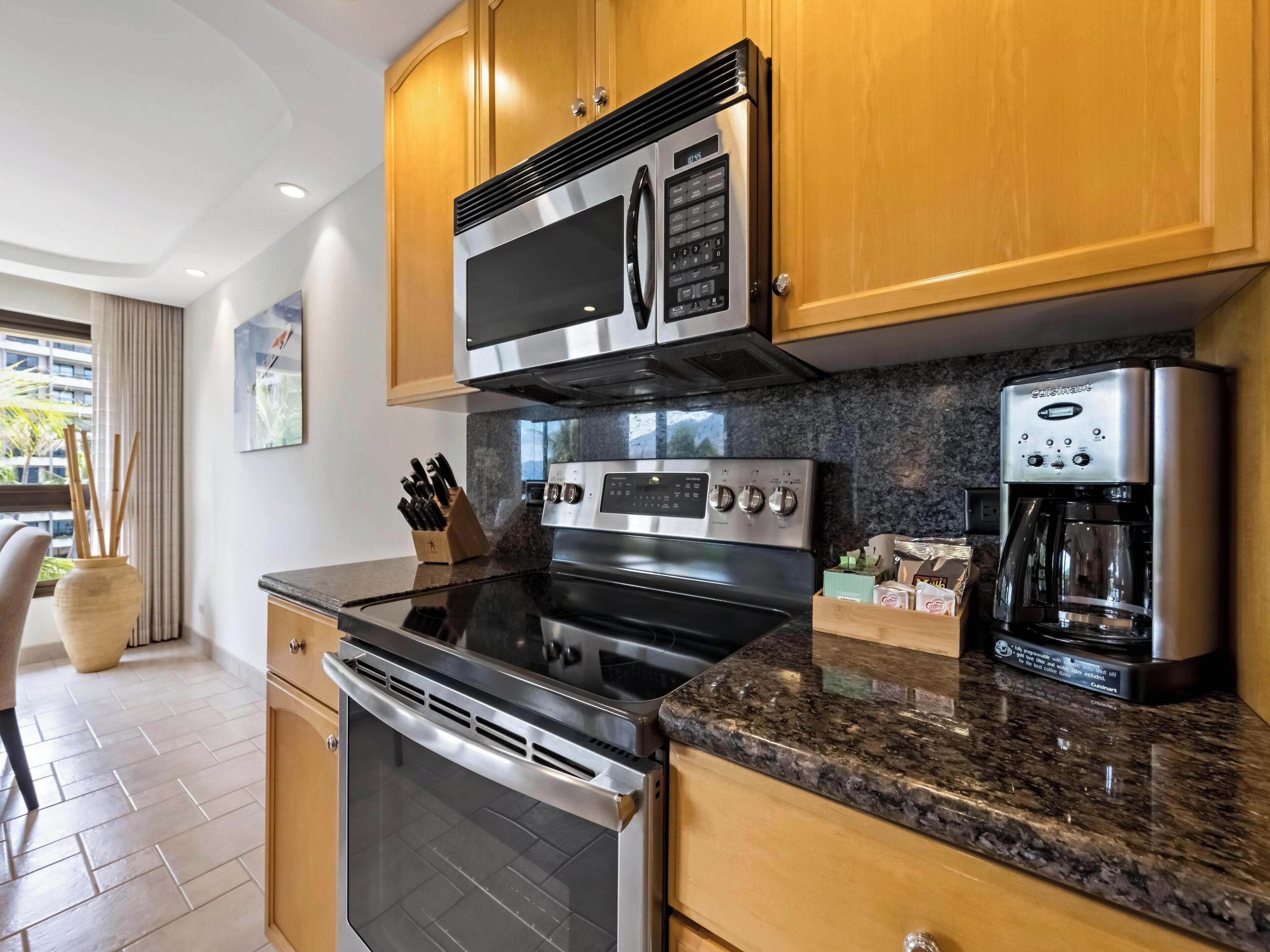 A modern kitchen with stainless steel appliances, wooden cabinets, and a granite countertop.