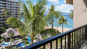 A hotel with a pool, palm trees, and a view of the beach and ocean.