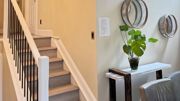 A staircase with white railings and wooden steps, a wall-mounted light fixture, and two framed windows.