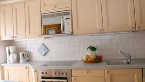 Een keuken met houten kastjes, een ingebouwde magnetron, een fornuis en een spoelbak.