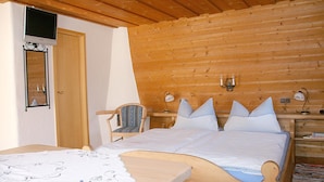 Een slaapkamer met houten lambrisering, een bed, een stoel, nachtkastjes en een spiegel.