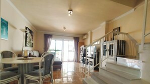 A spacious living area with a dining table, chairs, a sofa, and a staircase leading to another level. - Nerja Sun Apartments Casa Cipreses 5 (Nerja)