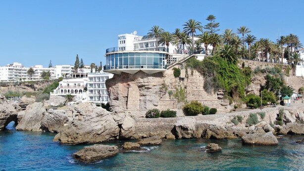 A hotel with a modern design, situated on a rocky coastline with clear blue waters. - Nerja Sun Apartments Casa Cipreses 5 (Nerja)