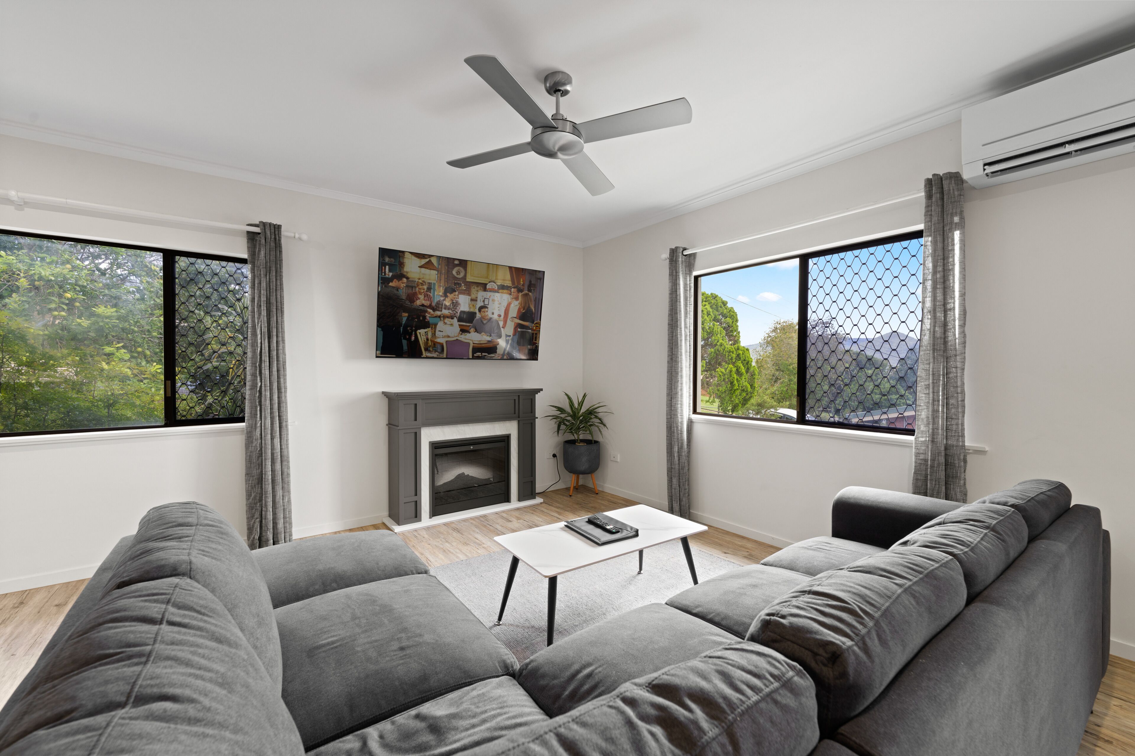 Una sala de estar moderna con un sofá gris, una mesa de centro blanca y una chimenea.