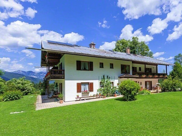 A two-story house with a balcony, a small porch, and a well-maintained lawn.