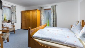 A bedroom with a wooden bed, two chairs, a wardrobe, and curtains. - Vacation apartment Hirscherl, 1-2 persons, 55 sqm (Schönau am Königssee)